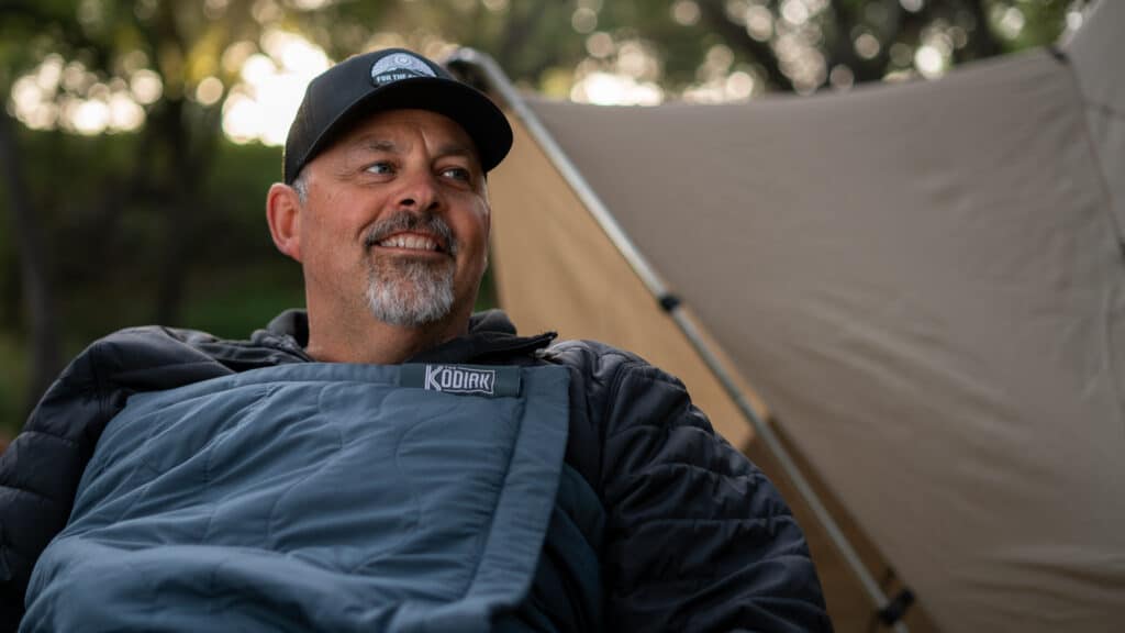 Man staying warm camping with the Kodiak Battery Powered Heating Blanket